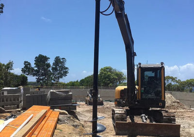 Excavator with auger attachment drilling post holes